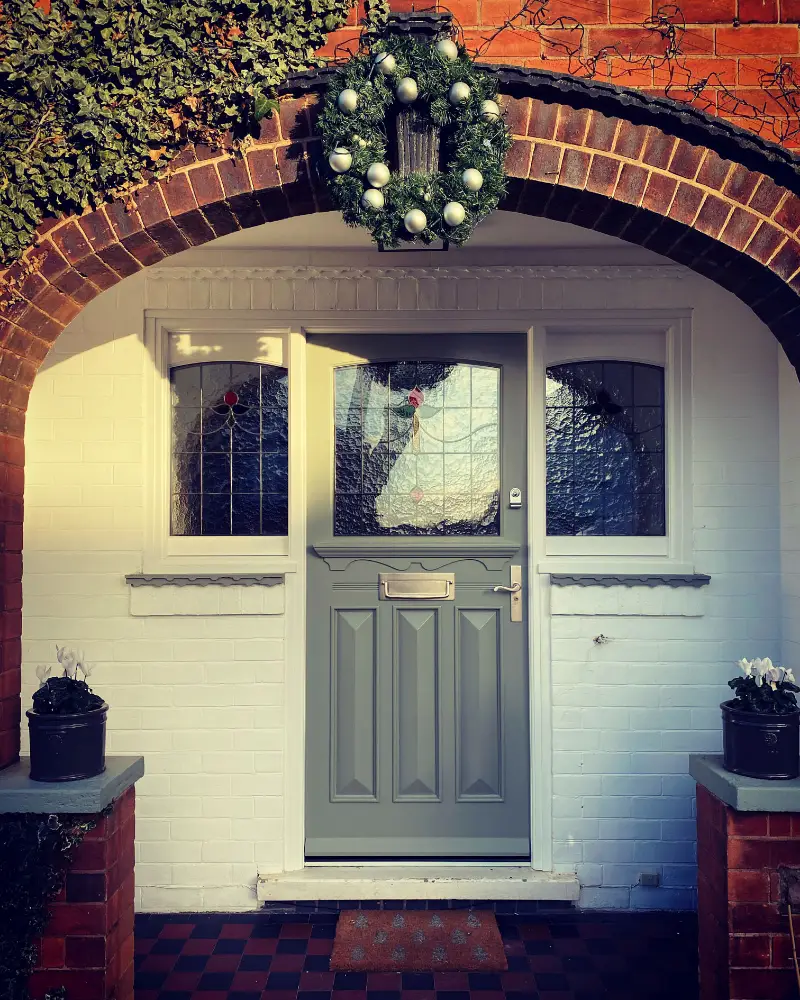 1930s-style timber front door with leaded glass panels, set beneath an arched porch with matching leaded side windows