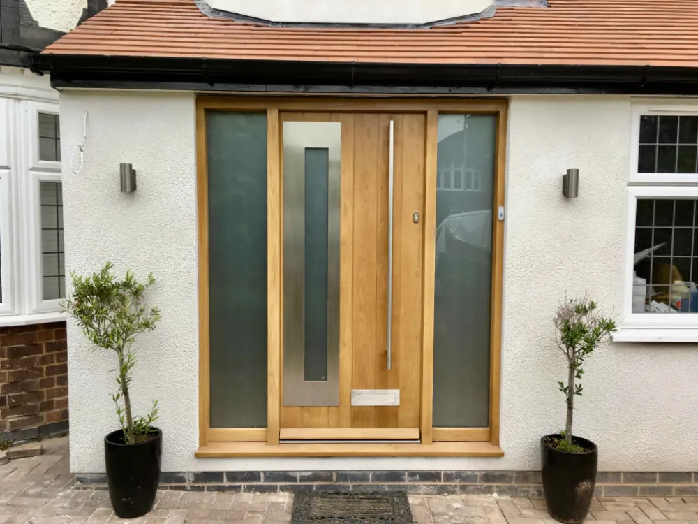 Contemporary natural oak front door with a tall glazed sidelight on a rendered house