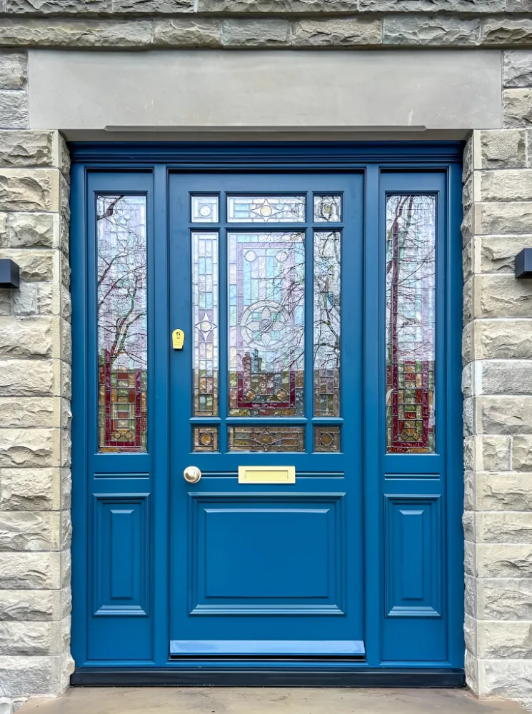 Deep blue painted timber front door with glazed panels on a stone-faced house
