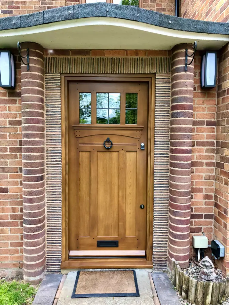 Natural oak Arts and Crafts style front door with small glazed upper panes and a black ring knocker, set in a brick house