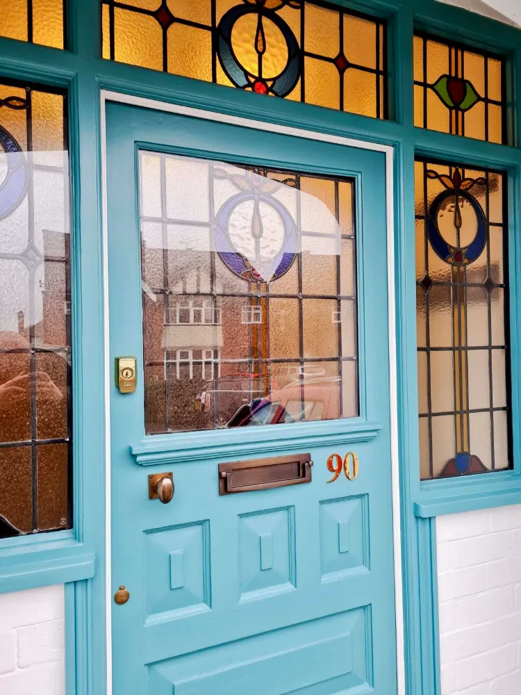 Teal painted timber front door with leaded glass panels set in a brick wall