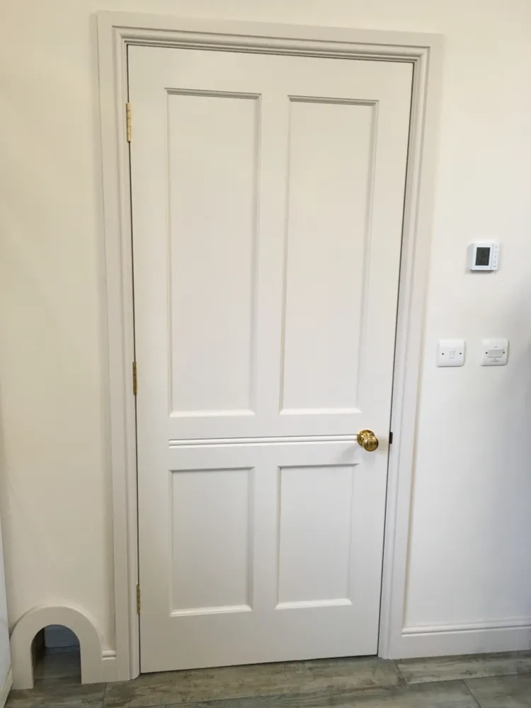 White painted panelled internal door set in a plain white wall