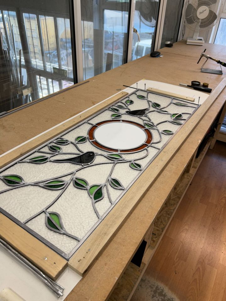 White curved bay window with multiple glass panes, set in a red brick wall with decorative molding and support brackets.
