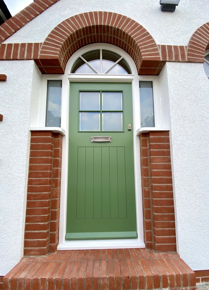 Elegant grey front door with ornate stained glass panels and matching sidelights and transom, featuring colourful geometric and floral designs, framed by an arched porch.
