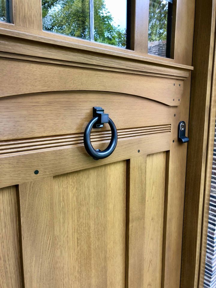 Elegant grey front door with ornate stained glass panels and matching sidelights and transom, featuring colourful geometric and floral designs, framed by an arched porch.