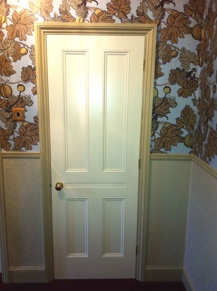 Black front door with an ornate arched stained glass panel featuring floral designs, flanked by matching side panels with decorative glass, set within a brick facade.