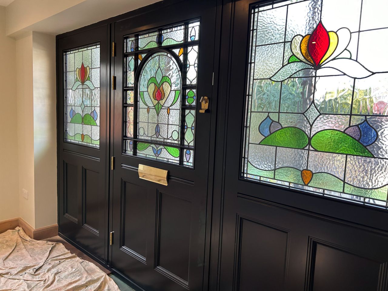 White bay window with multiple glass panes, framed by classical columns and set on a brick base, overlooking a garden.