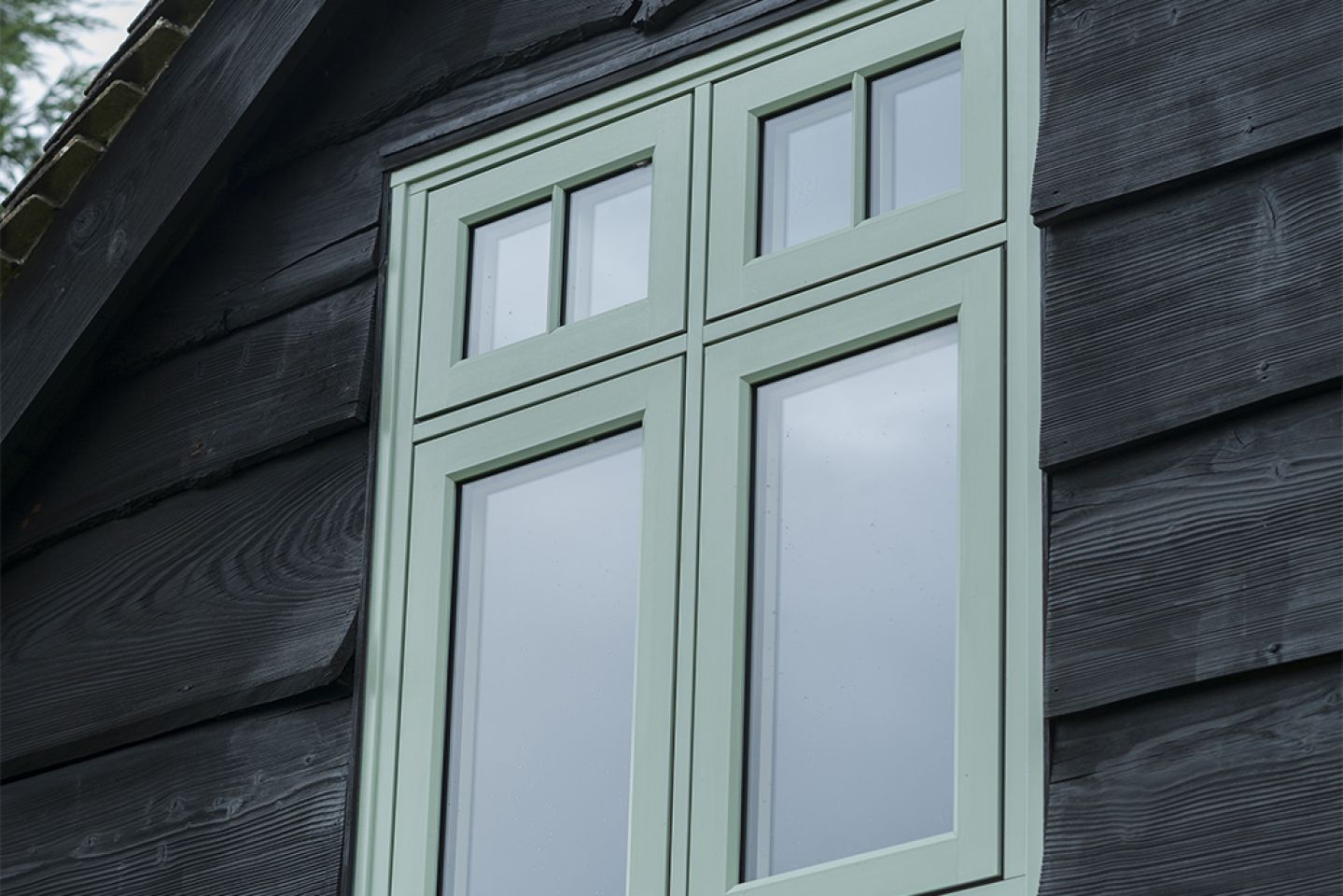 White curved bay window with multiple glass panes, set in a red brick wall with decorative molding and support brackets.