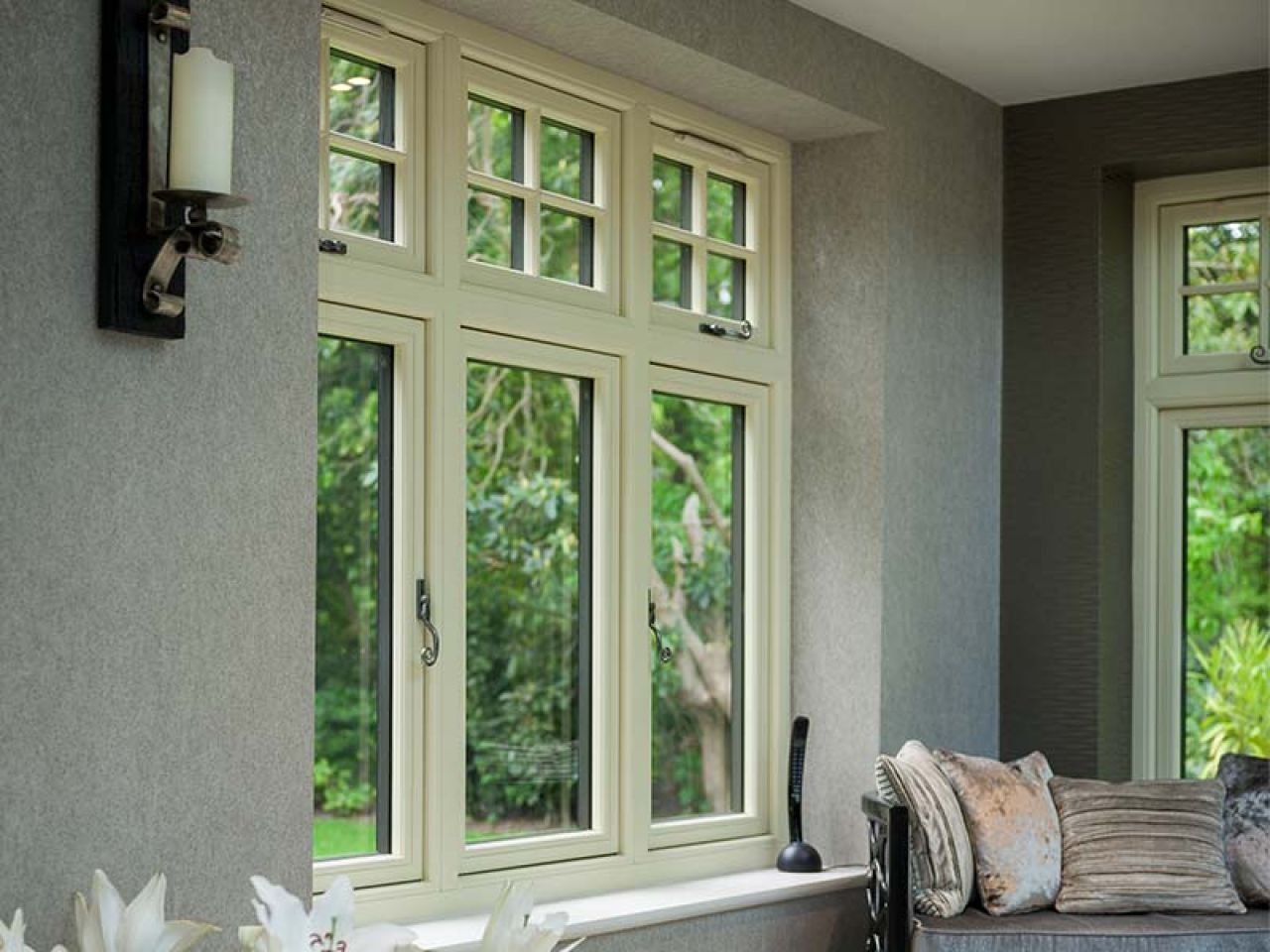 White wooden casement window with multiple glass panes, set in a red brick wall with an arched lintel and climbing vines.